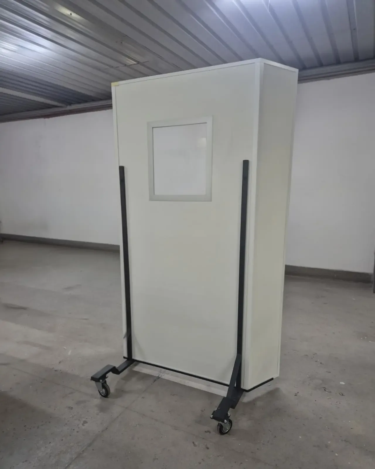 A mobile protective screen on castors with lead glass, in a production hall