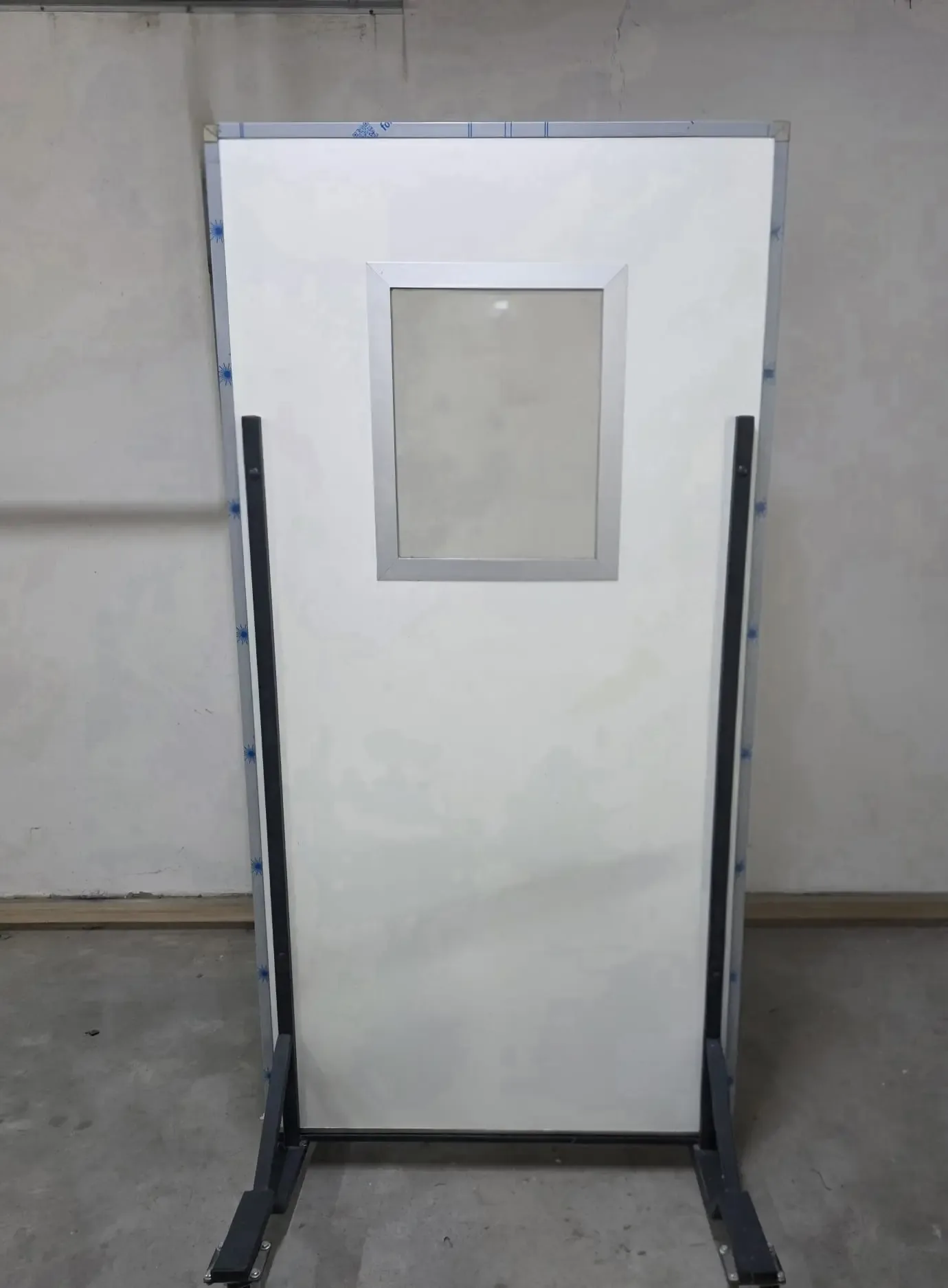 A mobile protective screen on castors with a smaller lead glass pane