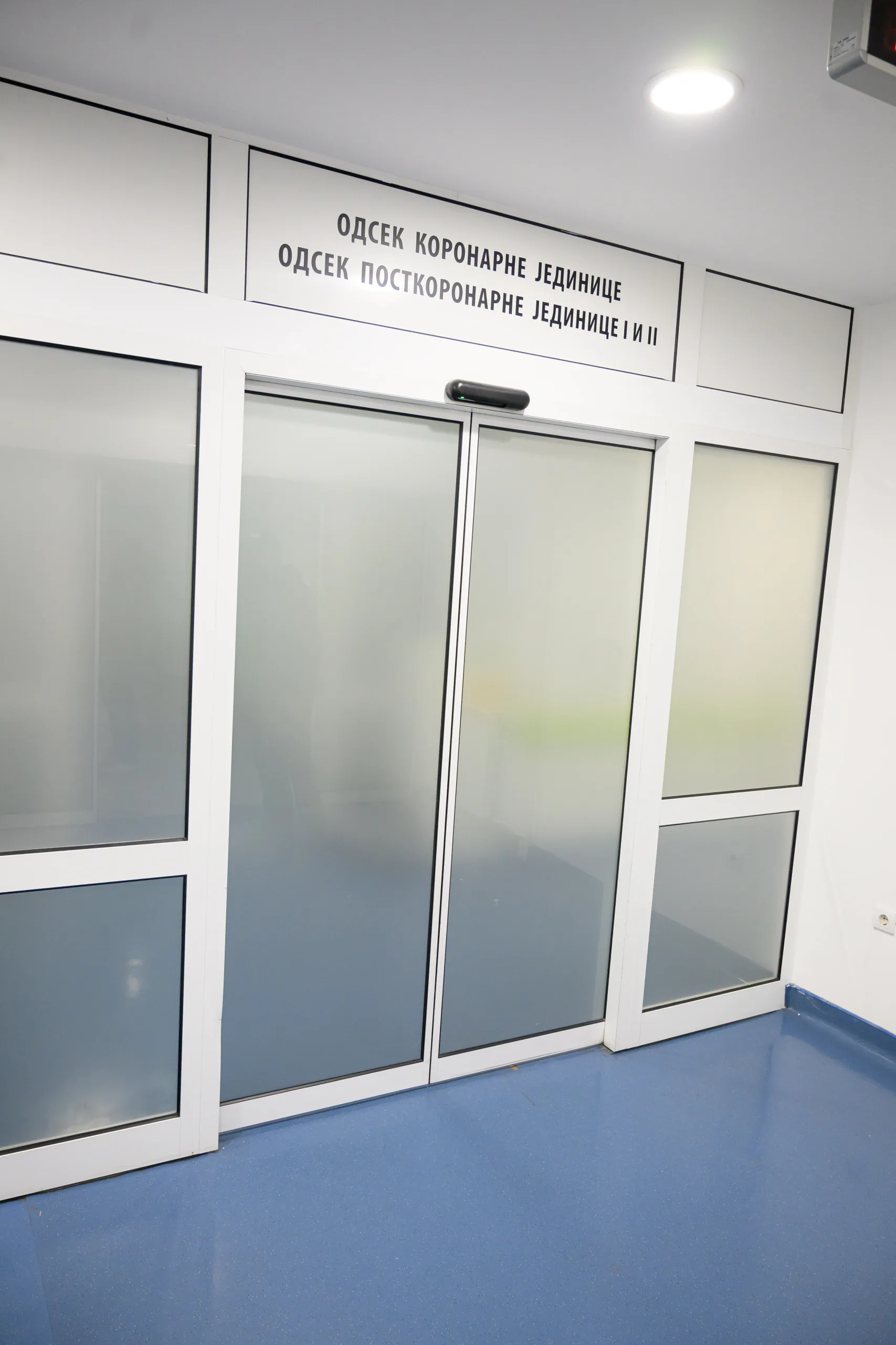 Automatic sliding doors with frosted glass and fixed side panels at the entrance to a hospital ward