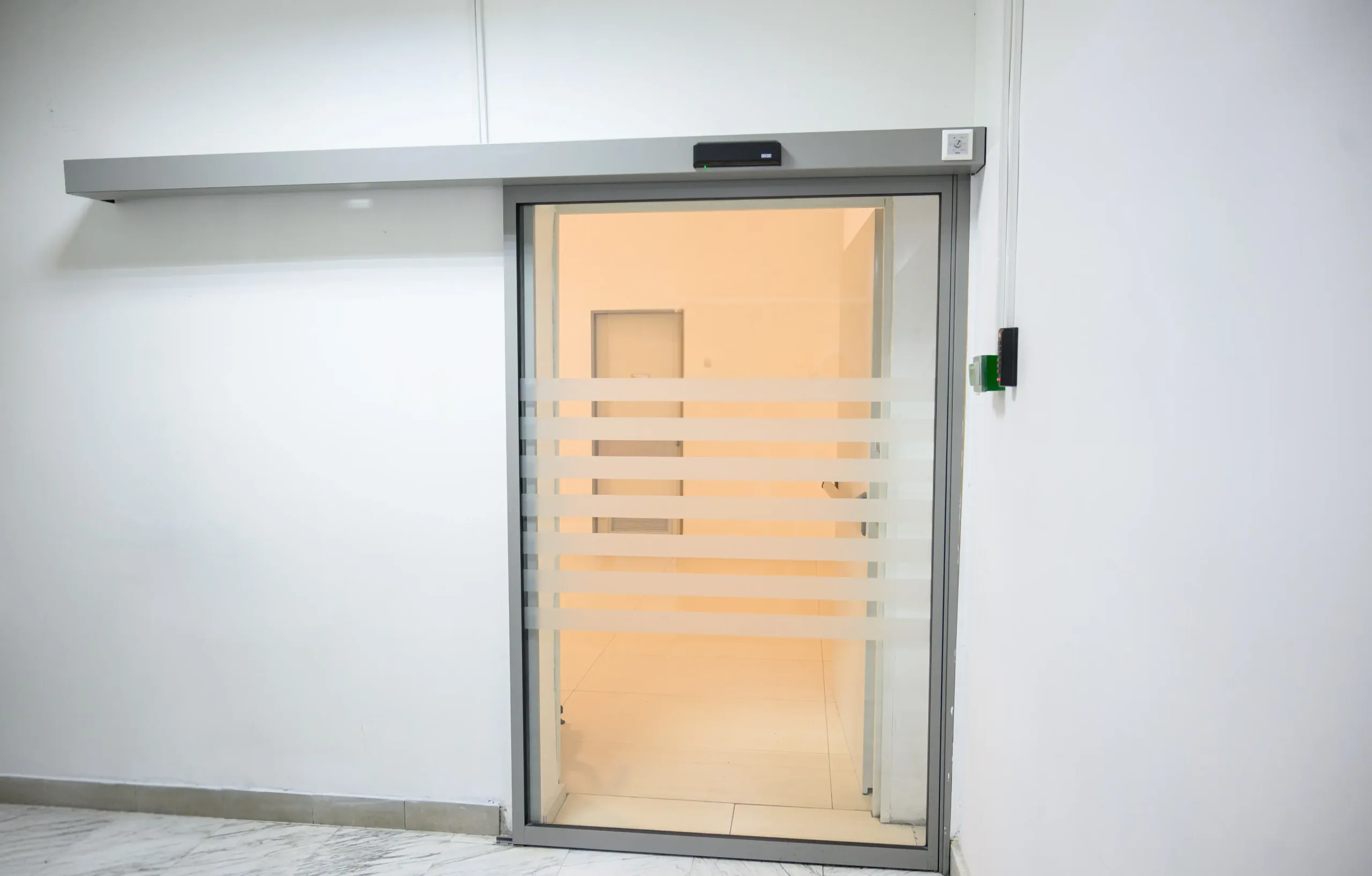 A single-leaf automatic sliding door with an aluminium frame and the drive in the transom
