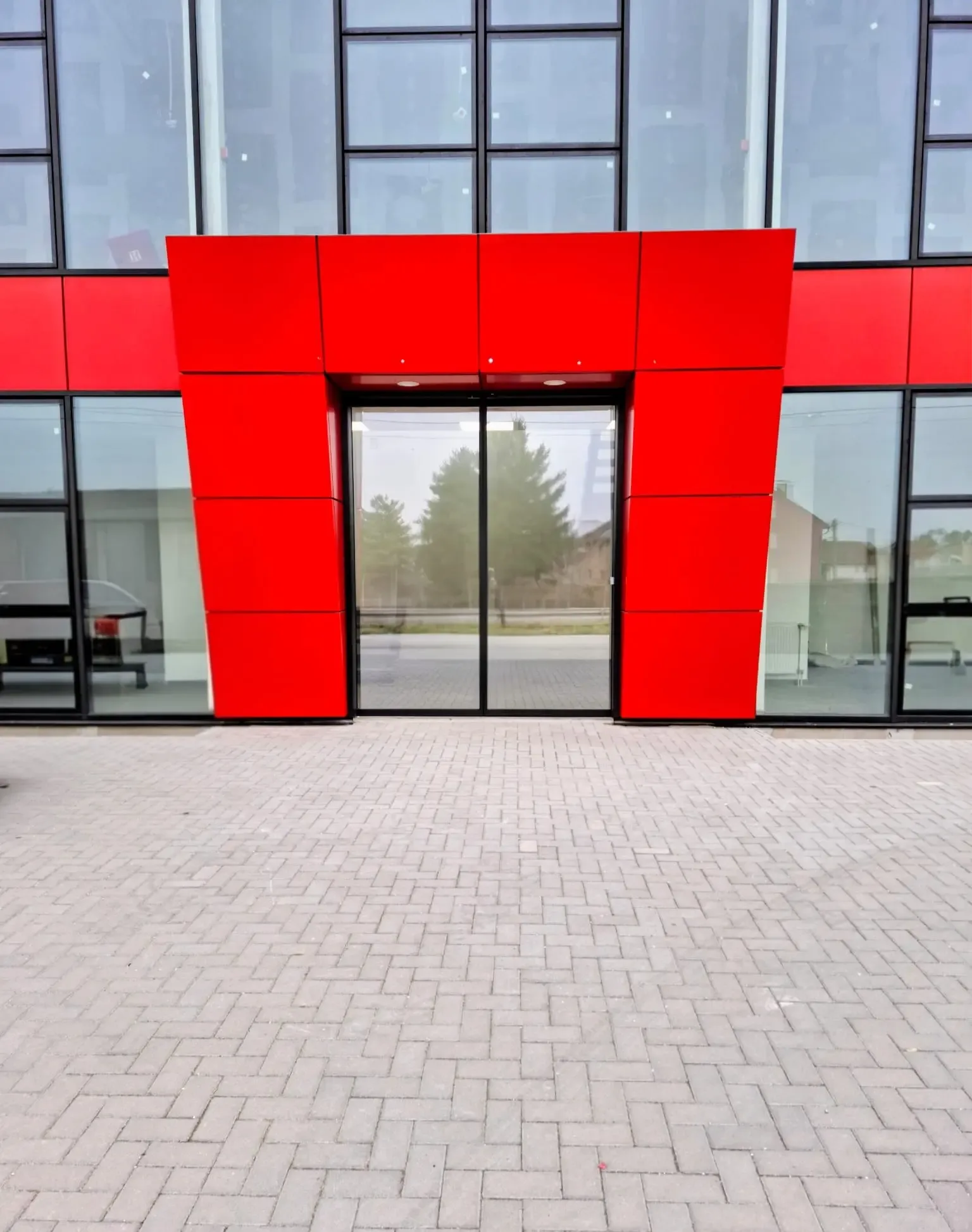 Glazed automatic sliding doors in the red entrance portal of an office building's glass façade