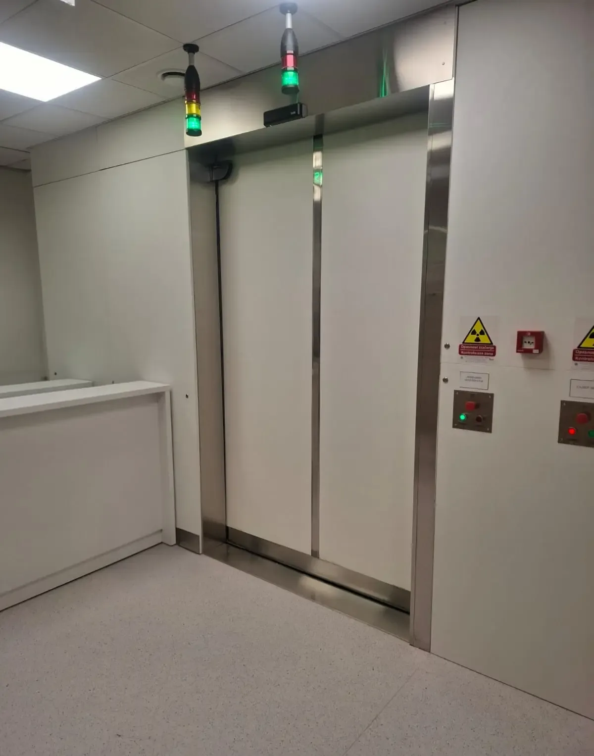 A massive sliding shielding door with stainless steel cladding, indicator lights and control buttons