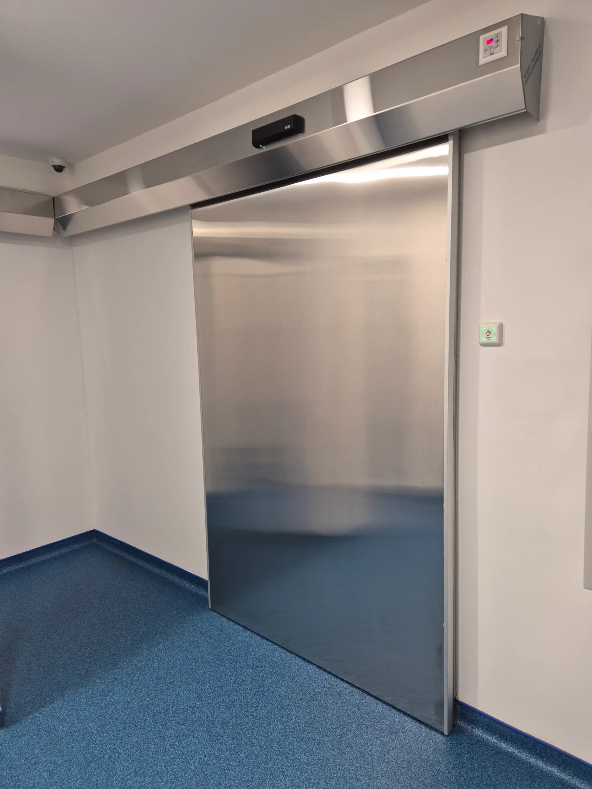 An open stainless steel hermetic sliding door with the drive in a stainless housing and indicator lights