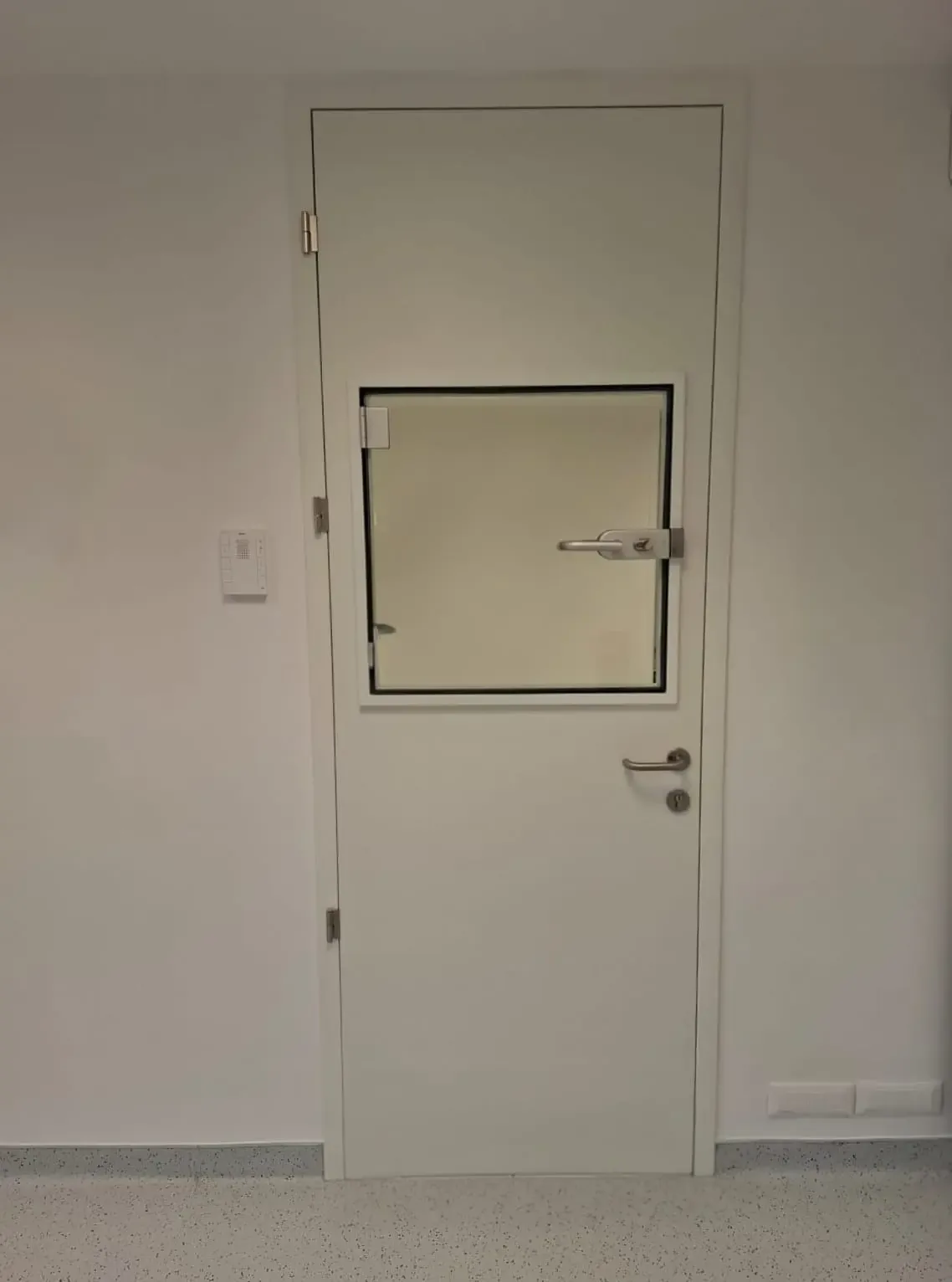 A lead-lined swing door with a lead glass vision panel and a metal frame
