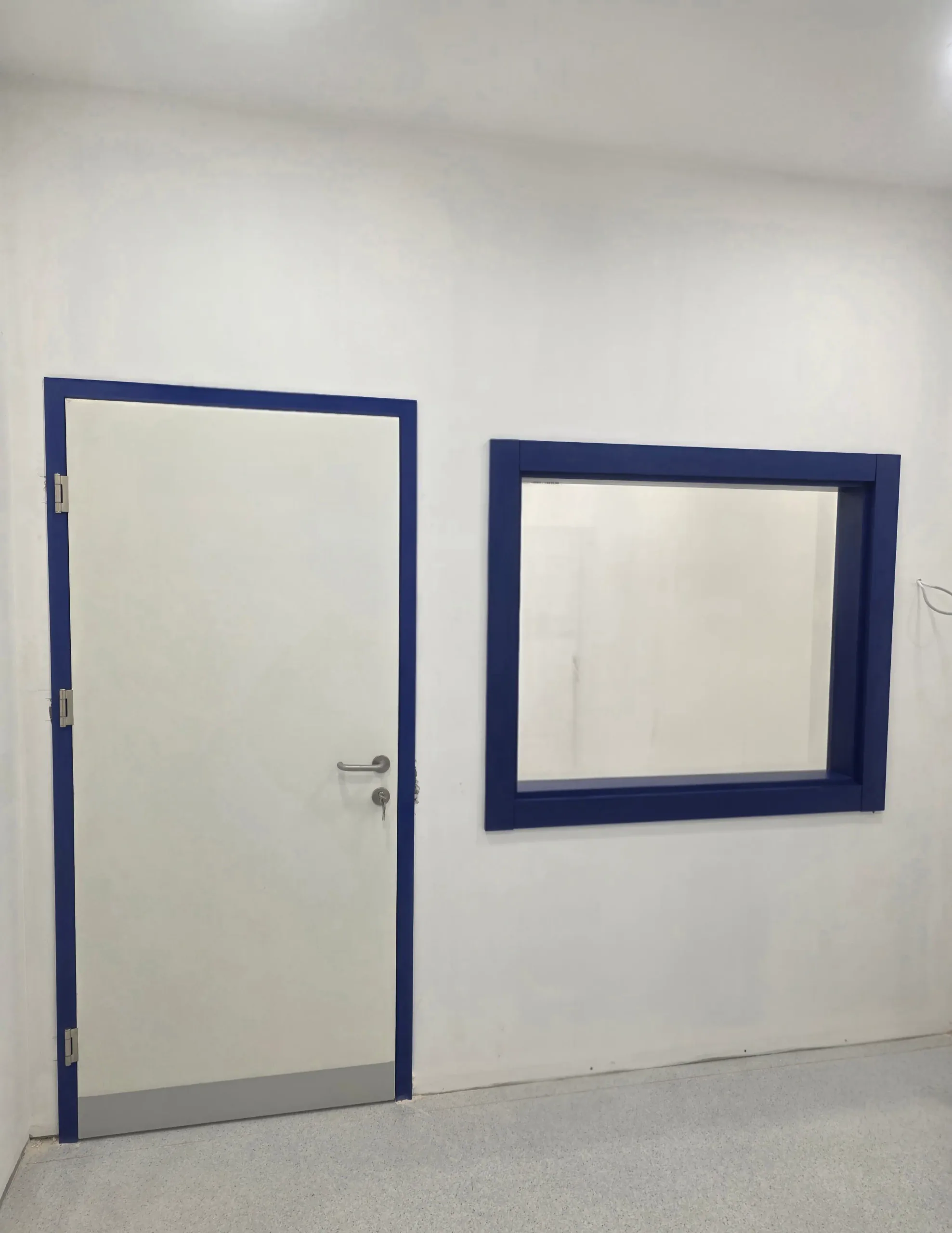 A lead-lined door and a protective lead window in blue frames, between an X-ray room and the control area