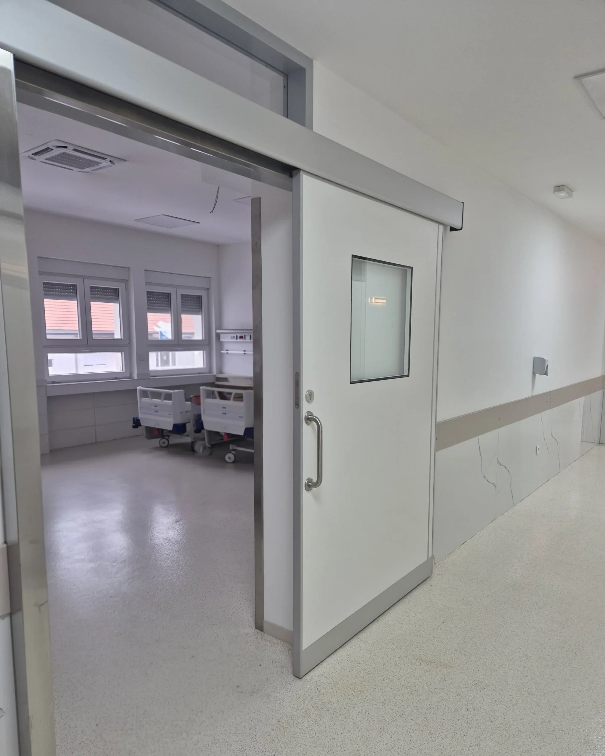An open sliding ward door with a vision panel and a long pull handle