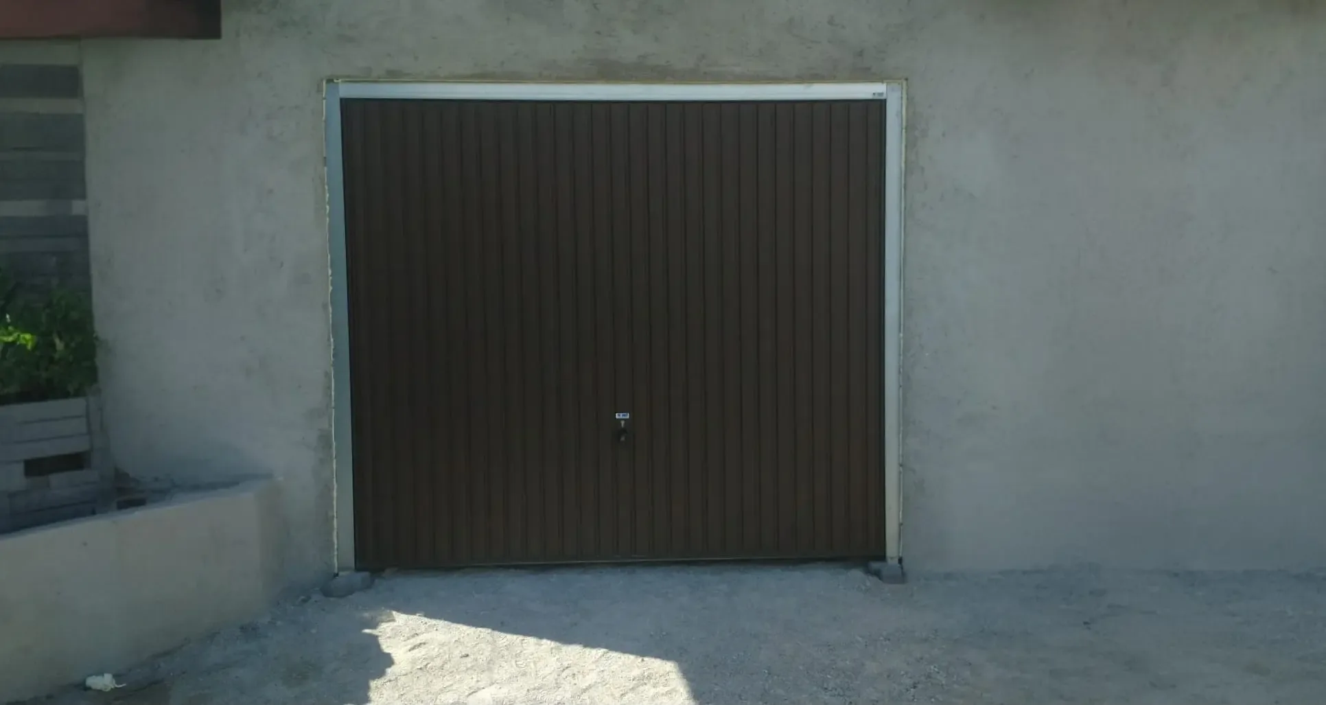 A dark brown up-and-over garage door with vertical ribbing on a house under construction