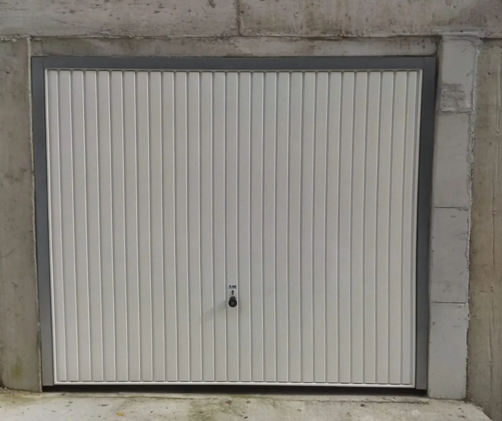 An up-and-over garage door with vertical ribbing in a concrete opening