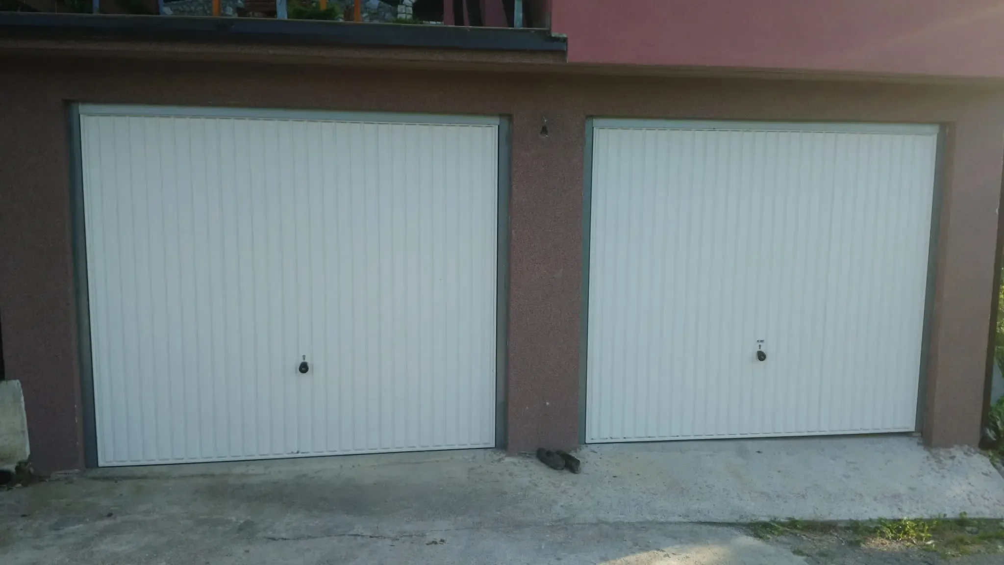 Two white up-and-over garage doors with vertical ribbing on a family house