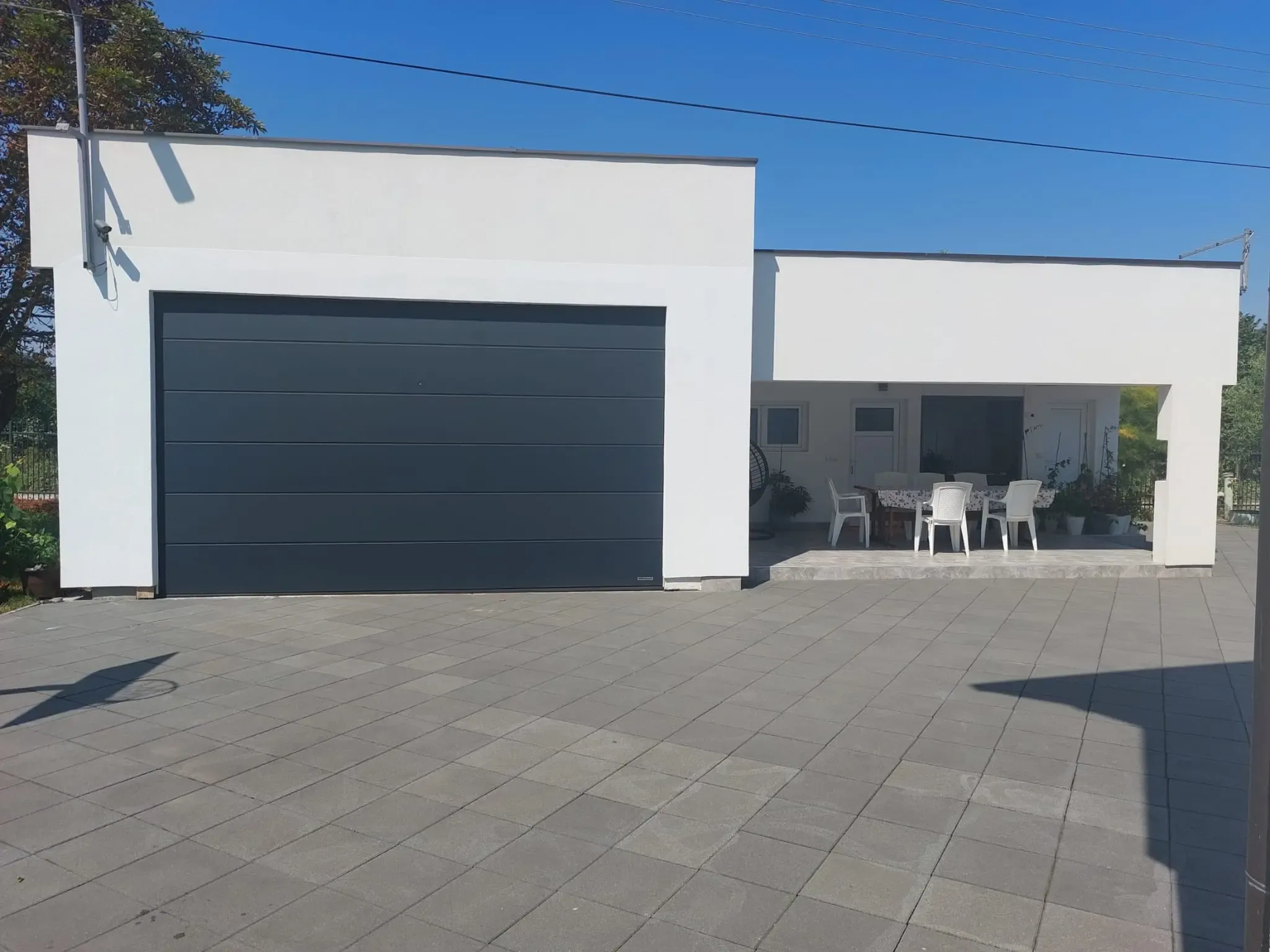An anthracite sectional garage door on the white façade of a contemporary house