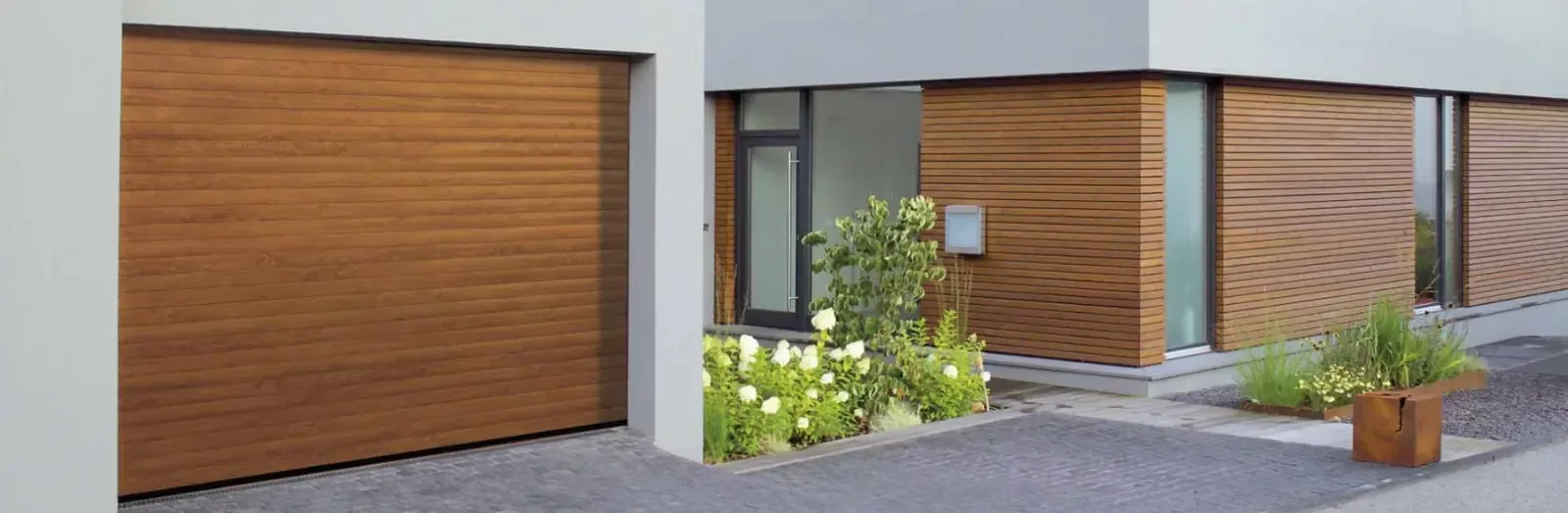 A roller garage door in a timber finish beside a façade clad in timber battens