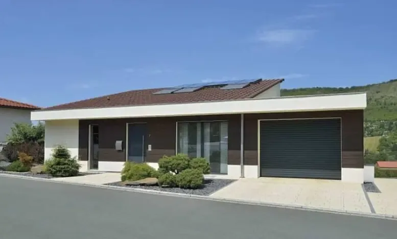 A dark garage door on a single-storey family house with a wide driveway