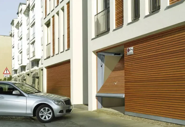 A communal garage door in a timber finish on a residential building, with the side door open