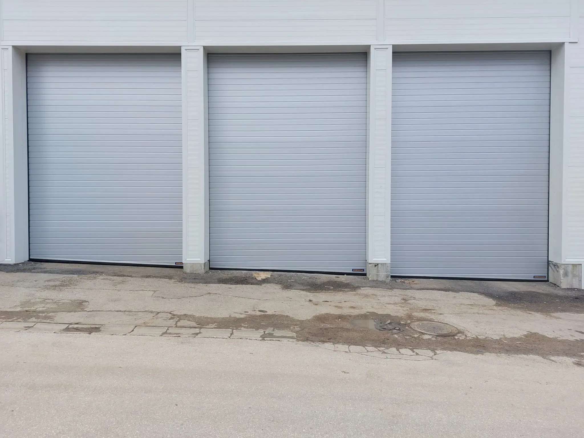 Three white sectional industrial doors without vision panels on the façade of a hall