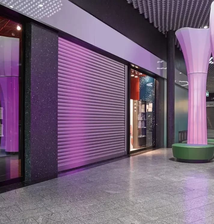 A roller shutter door with steel slats at the entrance to a unit in a shopping centre