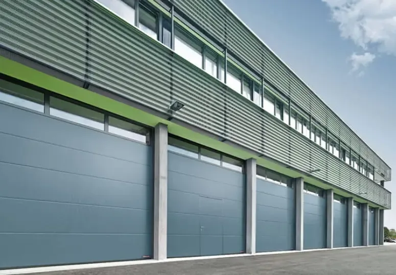 A row of sectional industrial doors along the façade of a hall, seen in perspective