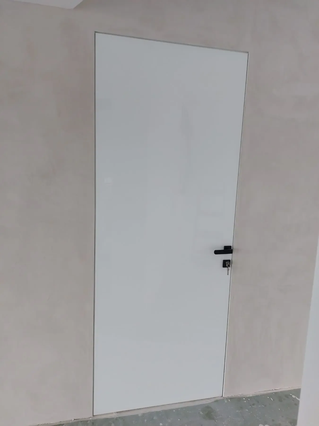 An interior door with a white leaf and a black lever handle in a space under construction