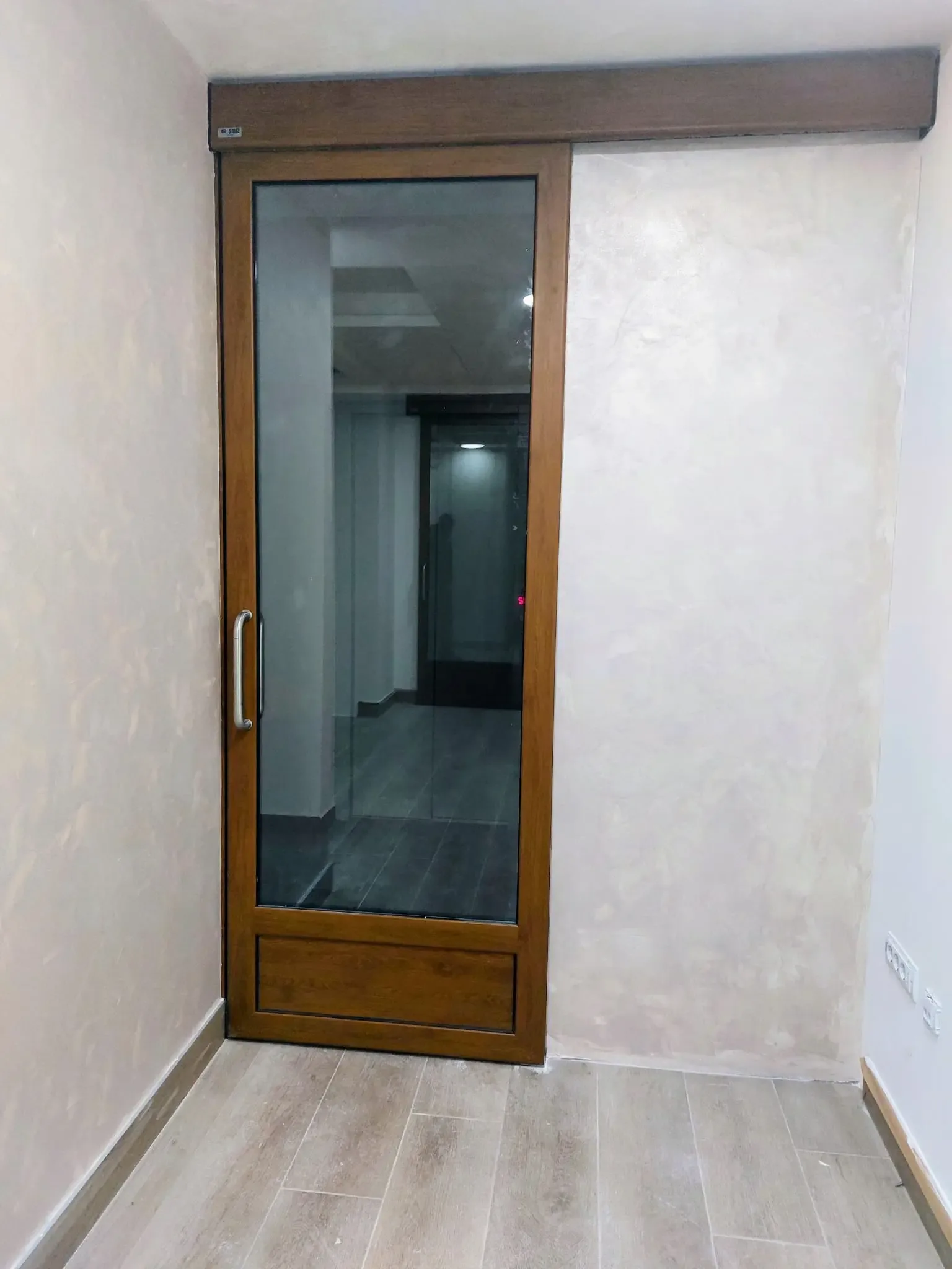 An interior sliding door with a glazed leaf in a timber frame and an exposed track above the opening